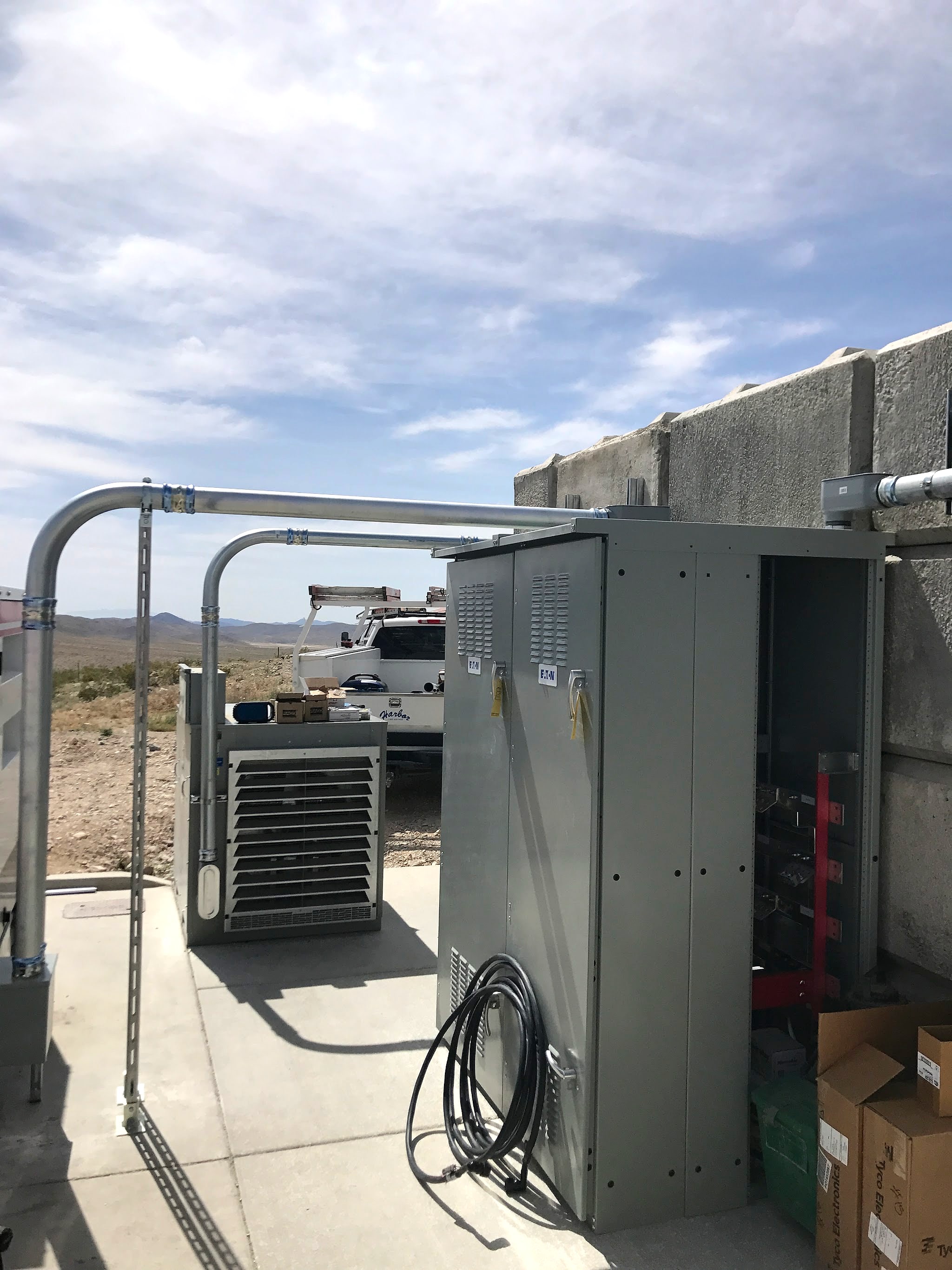 Outdoor service equipment with conduit runs, desert hills behind